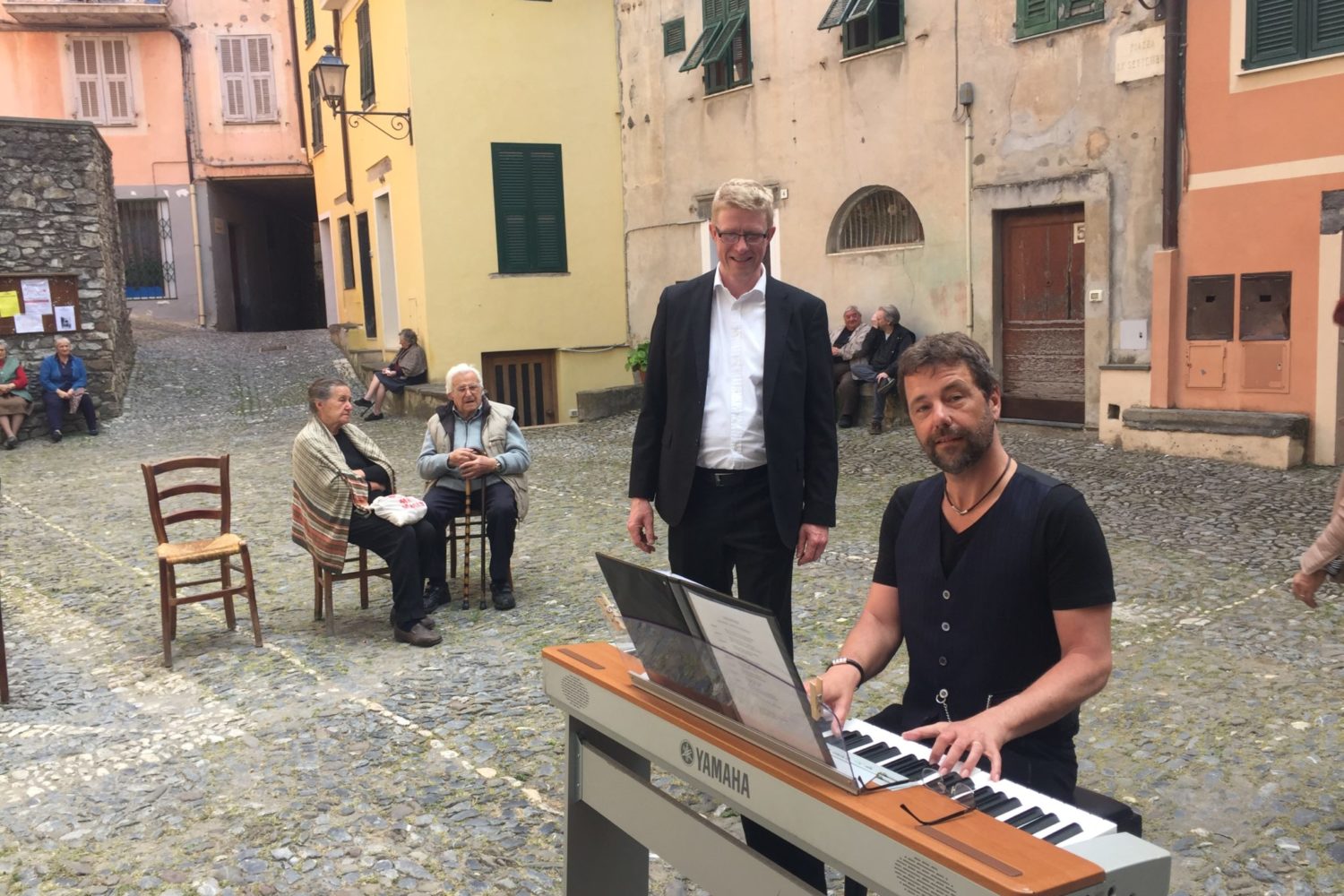 mand i jakkesæt synger med klaver på torv i Italien